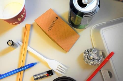 A variety of discarded items waiting to be sorted into the correct waste bin.