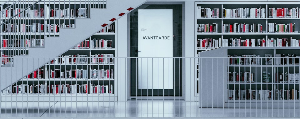 A library full of books and shelves with stairs in grey steel, with a door marked "Avant Garde."