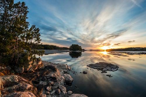 The sun rises over a lake.