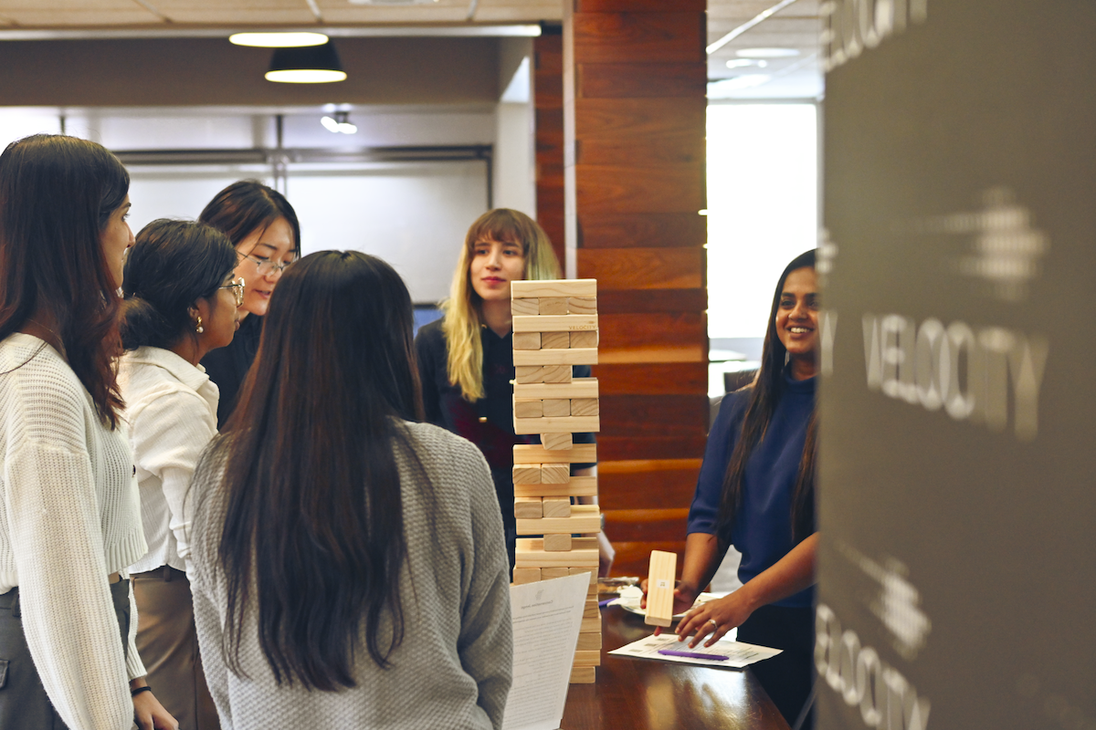 A group of young women play Jenga with oversized wooden blocks at a Velocity space.