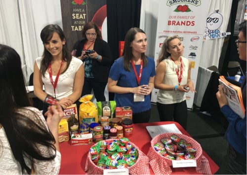 Representatives from the Smuckers jam company operate a booth at a career fair.