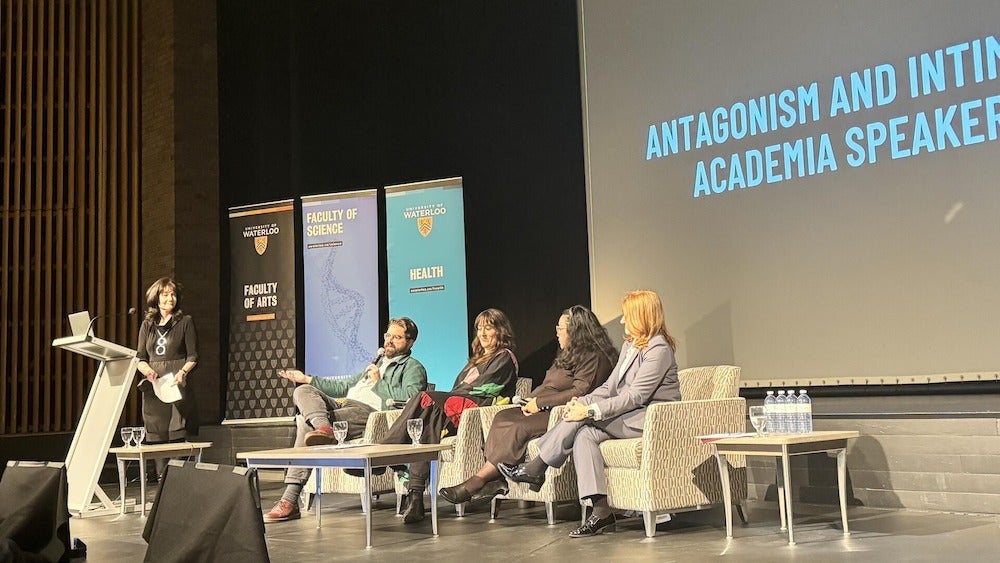 Moderator and panelists on stage in the Humanities Theatre.