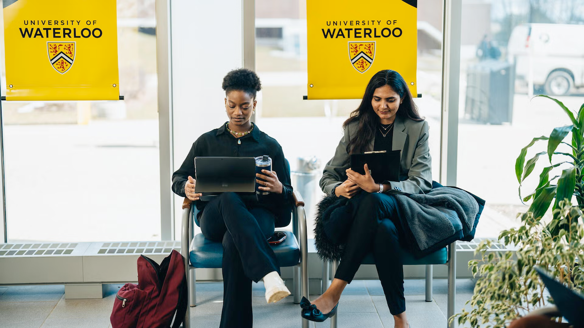 Two women sit with laptops open in the Tatham Centre lobby.