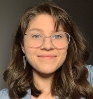 Headshot of Elizabeth Drew, a young woman with brown hair wearing glasses.