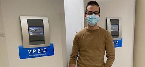 Pharmacy grad Daniel Pereira stands in front of computerized wall displays.