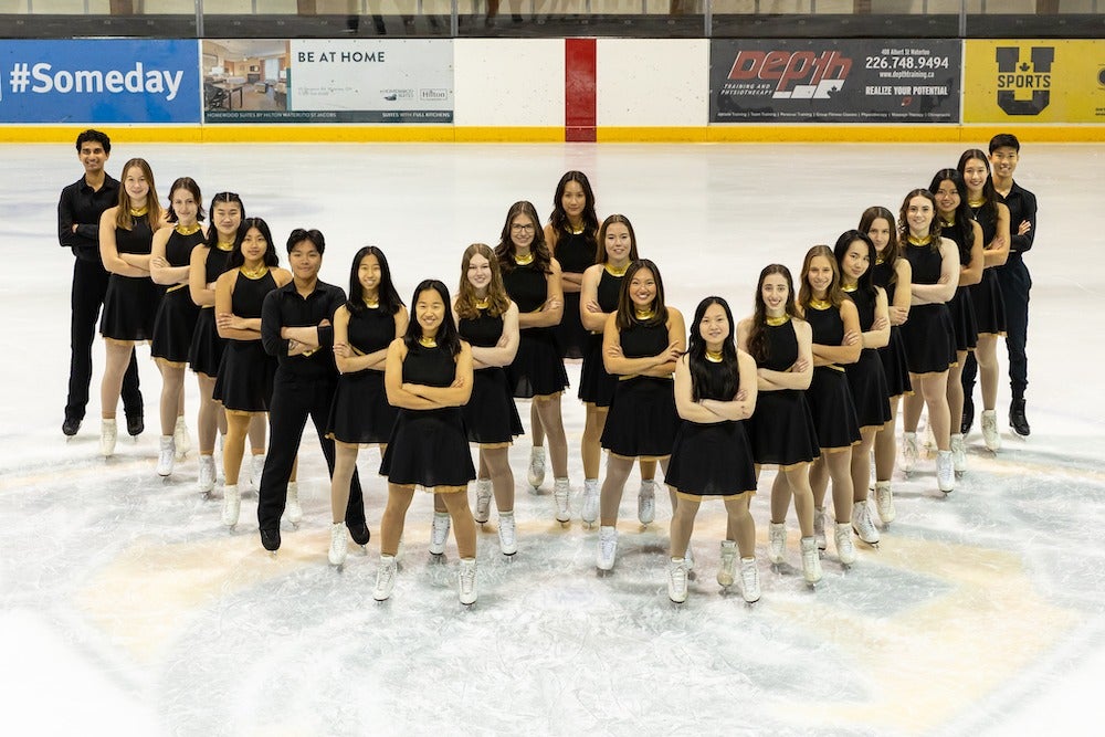 Members of the University of Waterloo figure skating program line up on the rice in a "W" shape