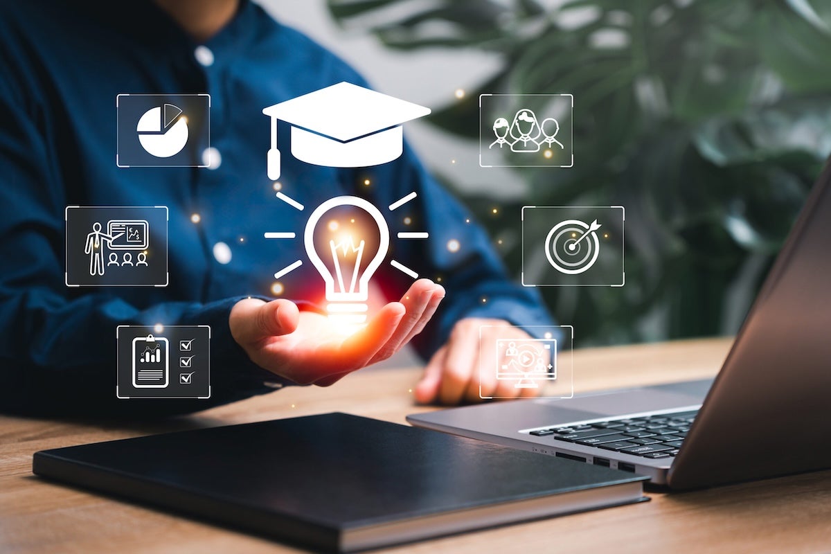 A person sits with a laptop, holding their hand out as a glowing light bulb and a graduation cap icon hover above it, surrounded by digital icons