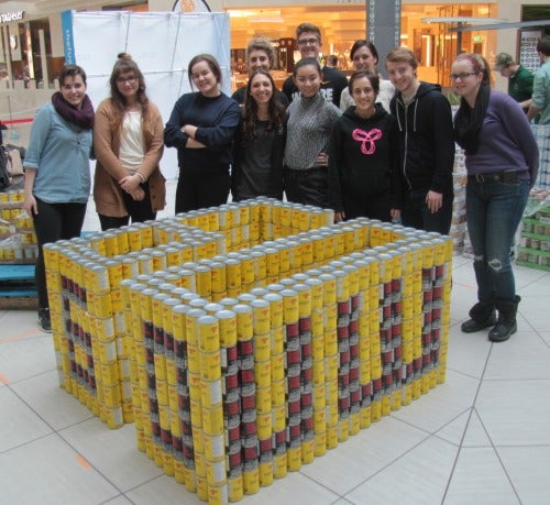 Student volunteers and their can sculpture that spells &quot;UW 60&quot; and is formed in the shape of the number 60.