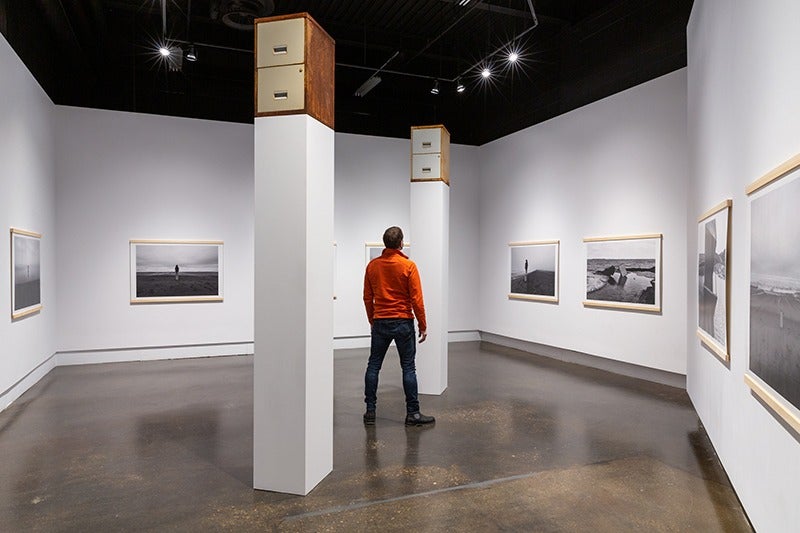 Filing cabinets sit atop pillars as a man looks up at them.