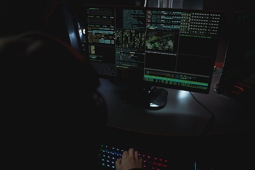 A hacker looks at a computer screen full of data.