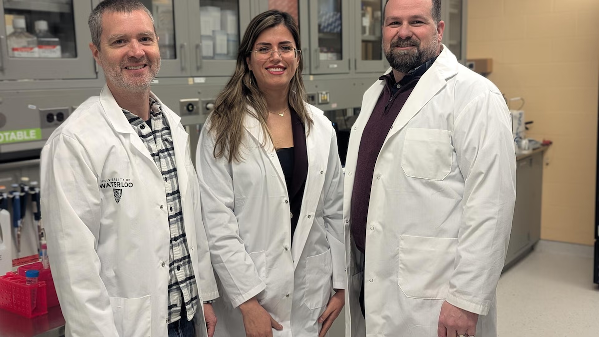Three researchers in white coats in a lab.
