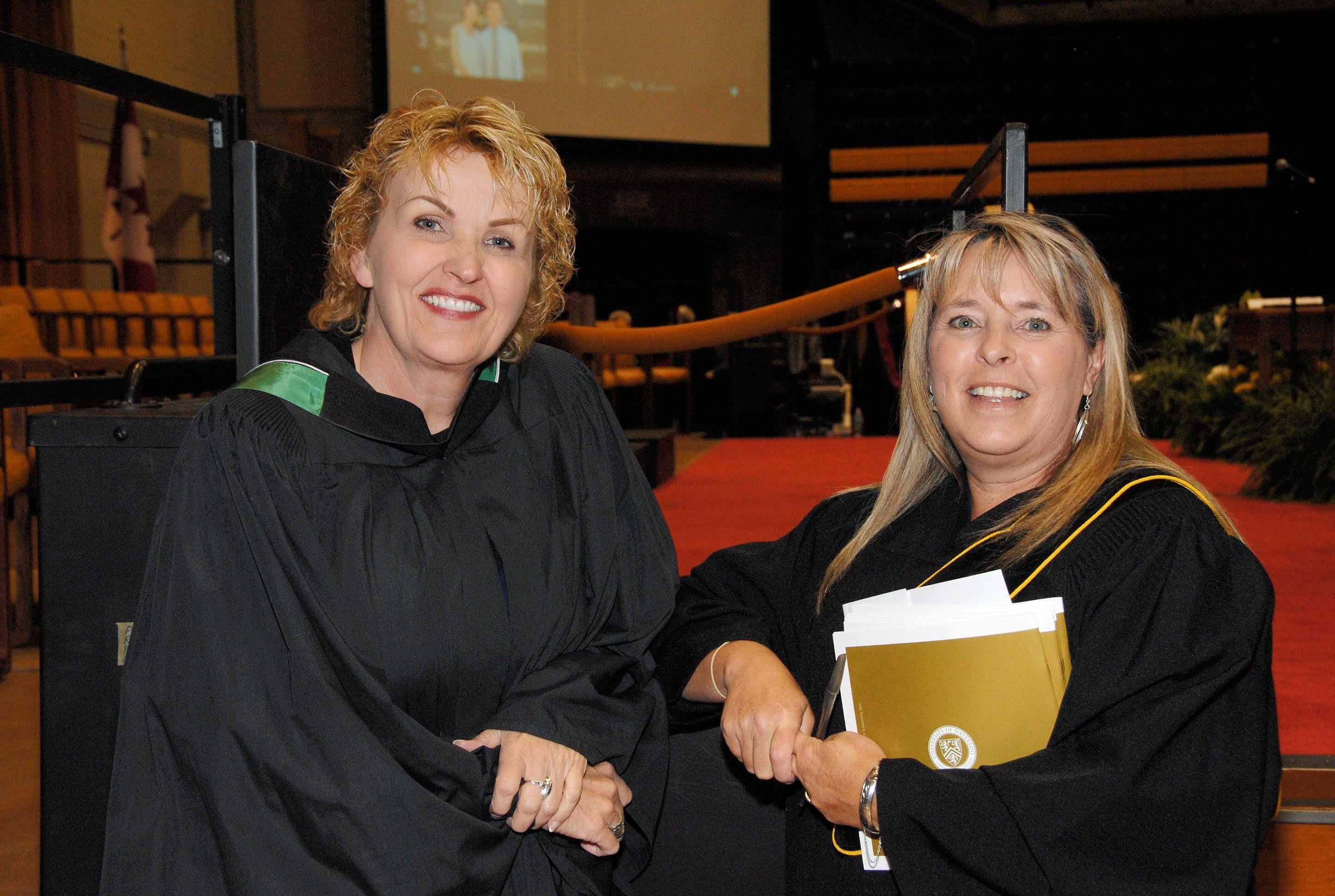Two employees wearing regalia volunteer at Convocation.