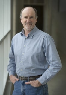 A man in a blue shirt standing with his hands in his pockets