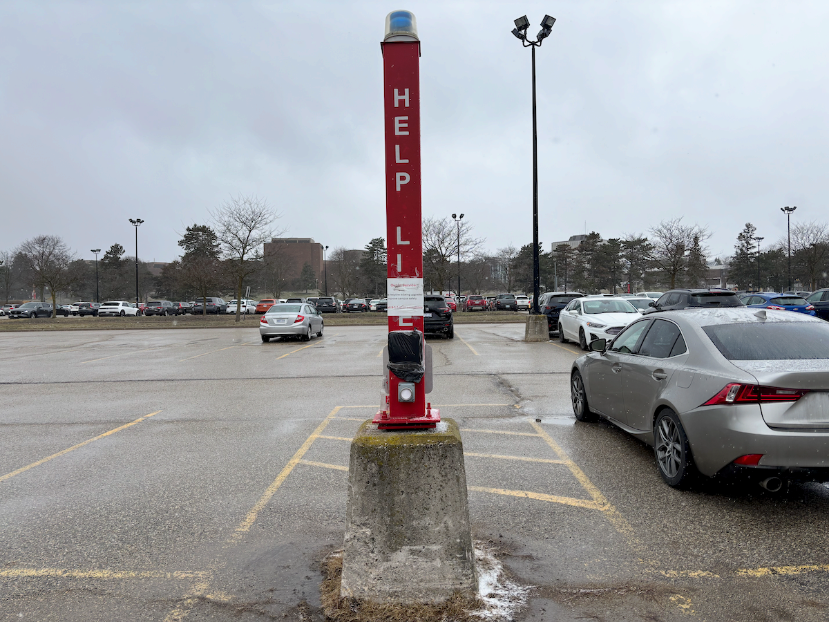 A red Help Line pole with a blue light on top in the University's c-lot.