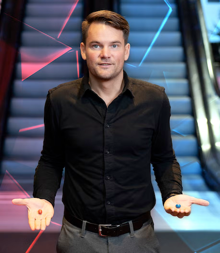 Sjors Groeneveld holds a red pill in one hand and a blue pill in the other.