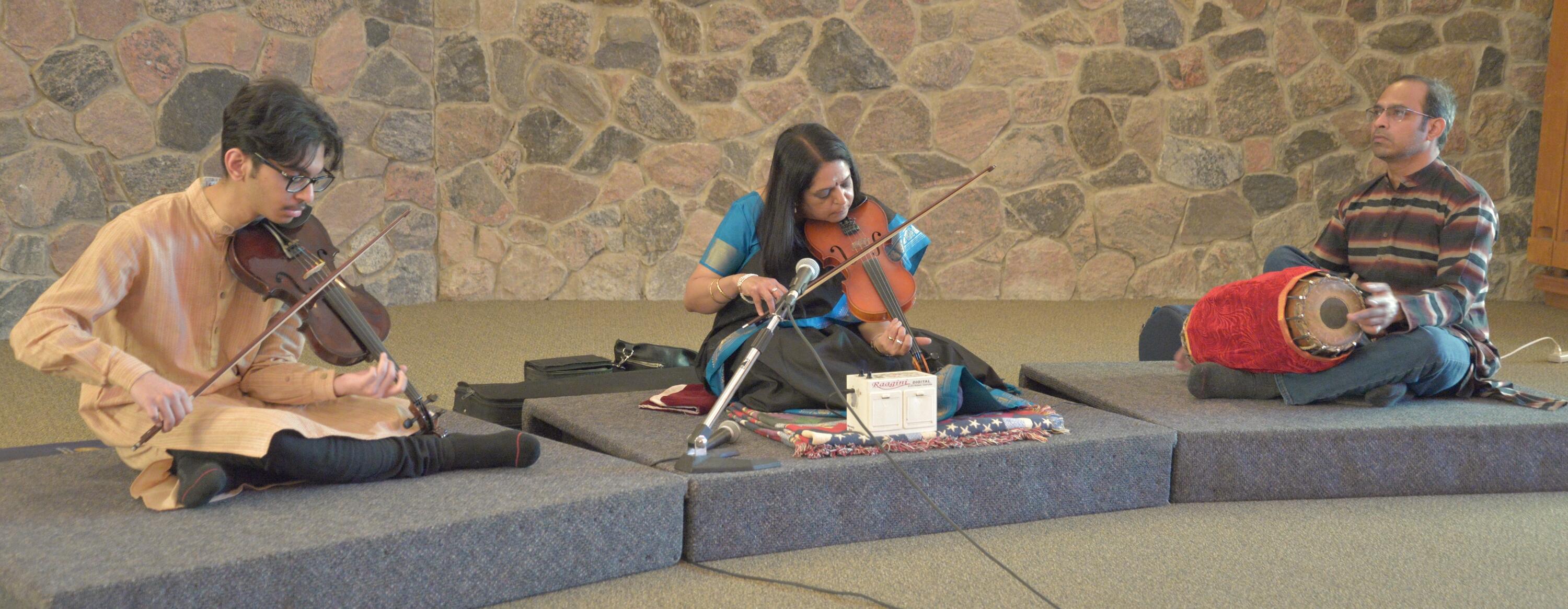 3 people playing violin at a desk