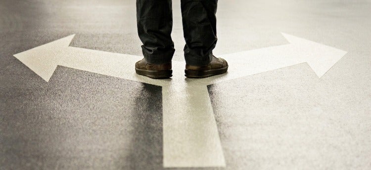 A person stands on a set of arrows pointing in opposite directions.