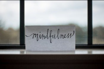 A postcard with the word "mindfulness" sits in front of a window.