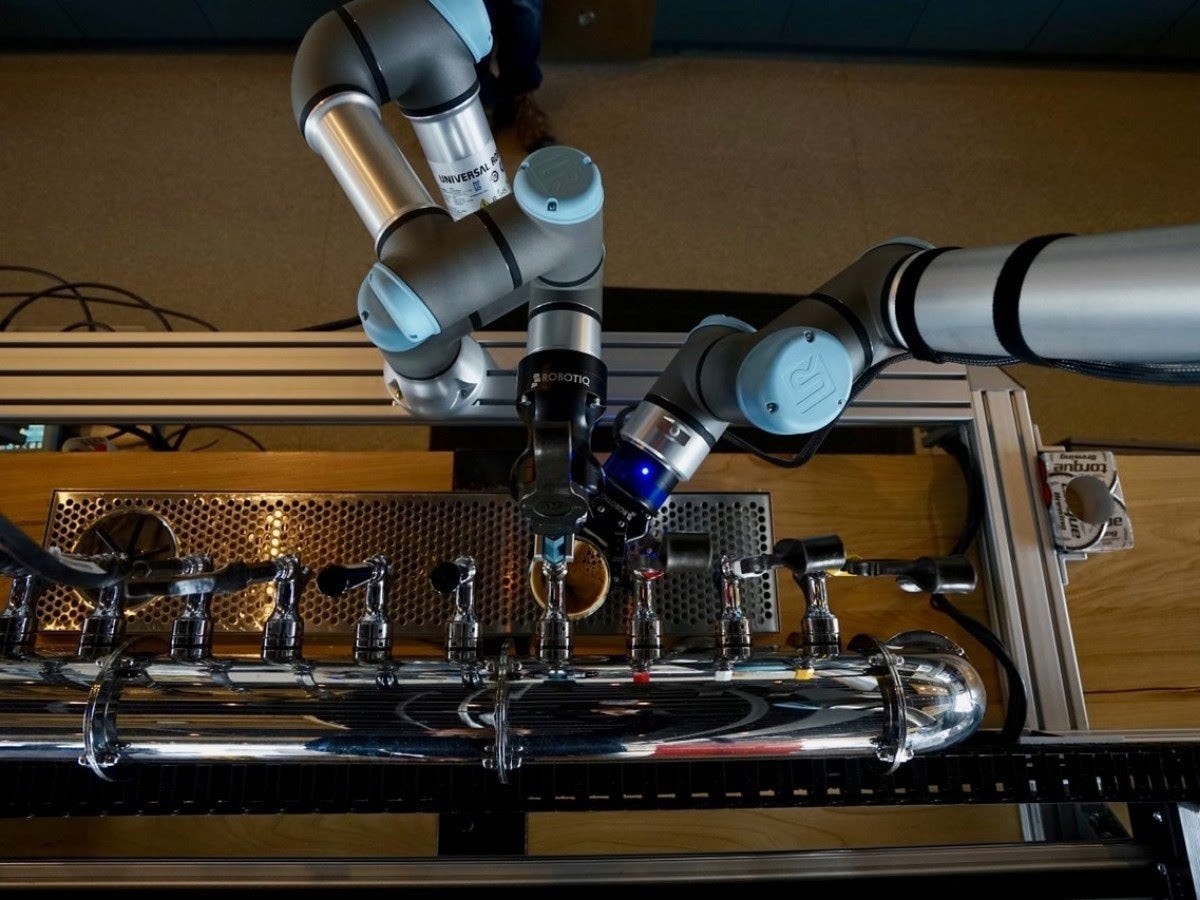 An overhead view of a bartender robot pouring a drink.