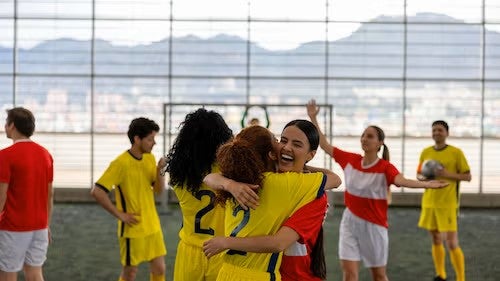 A stock photo of indoor soccer athletes hugging and celebrating.