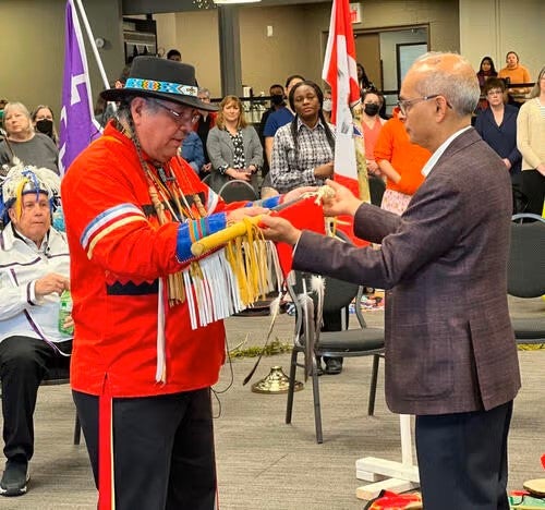 Myeengun Henry presents President Vivek Goel with the Eagle Staff.