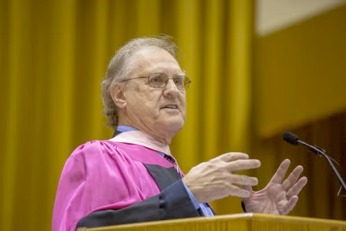 Stephen Lewis in convocation regalia while addressing the audience.