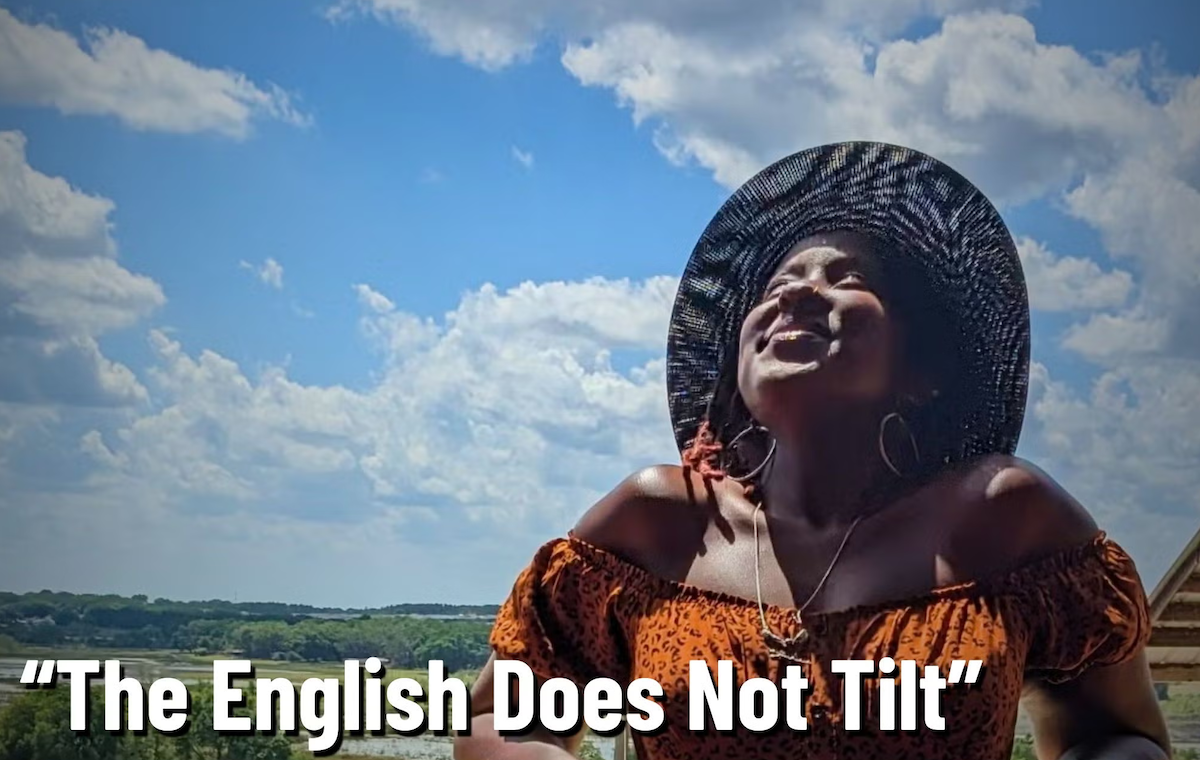 A woman wearing a hat tilts her head back to the sky.