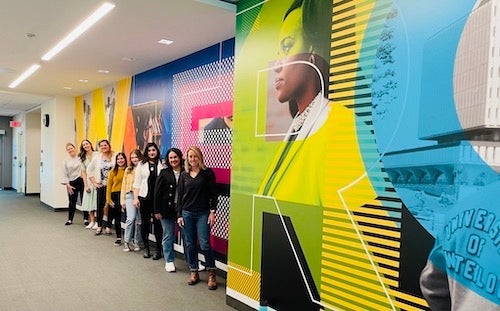 The UWaterloolife team poses for a group photograph in front of the new mural outside the Board and Senate chamber.