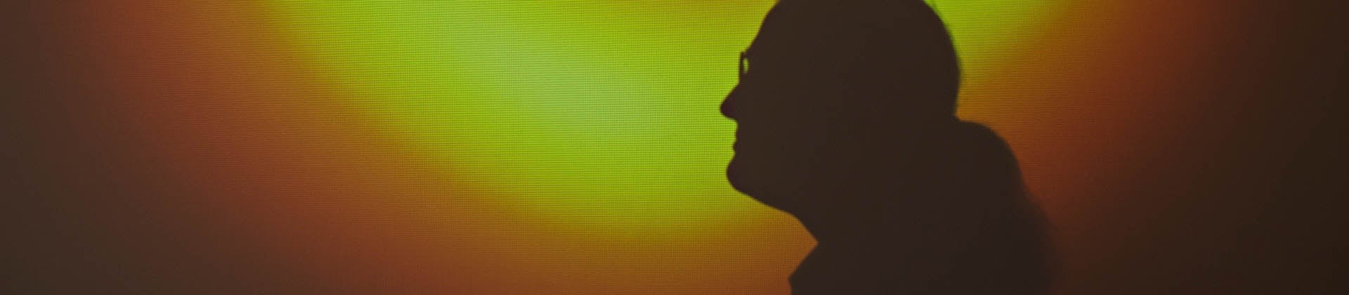 Professor Avery Broderick in silhouette against the black hole image.