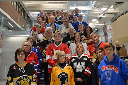 Members of the Faculty of Arts wearing jerseys stand together in the Hagey Hub.