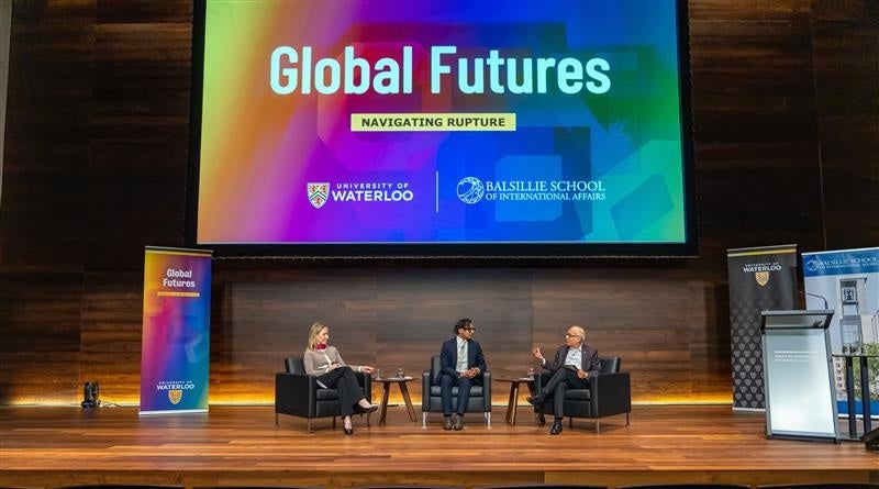 Dr. Ann Fitz-Gerald, Hamza Abdulbasit, and Dr. Vivek Goel seated on a stage.
