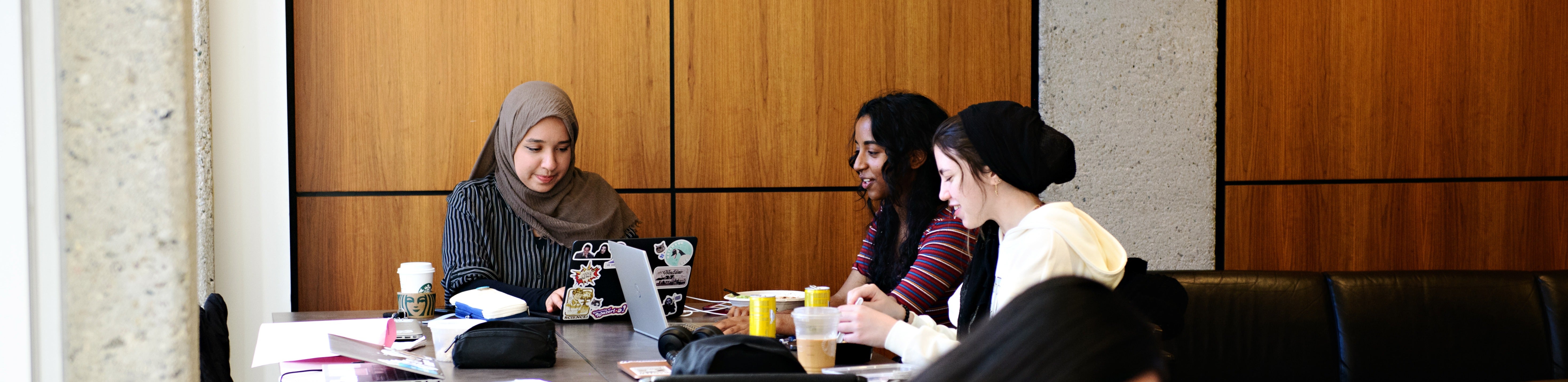 Three students study together in a lounge setting.