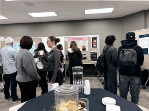 A group of students interacting in front of poster presentation boards.