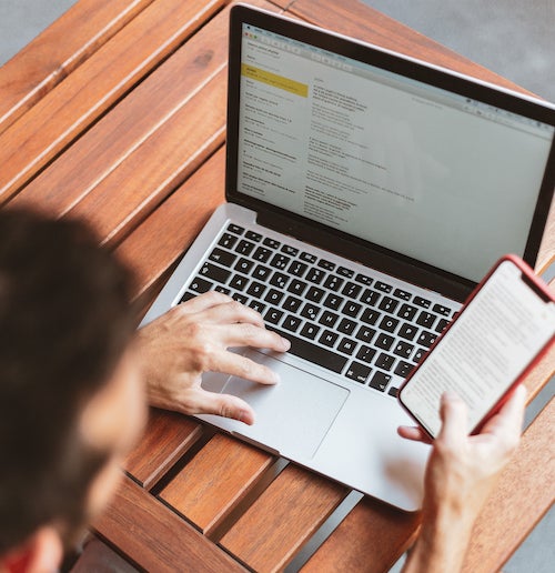 A person checks his phone and a laptop at the same time.