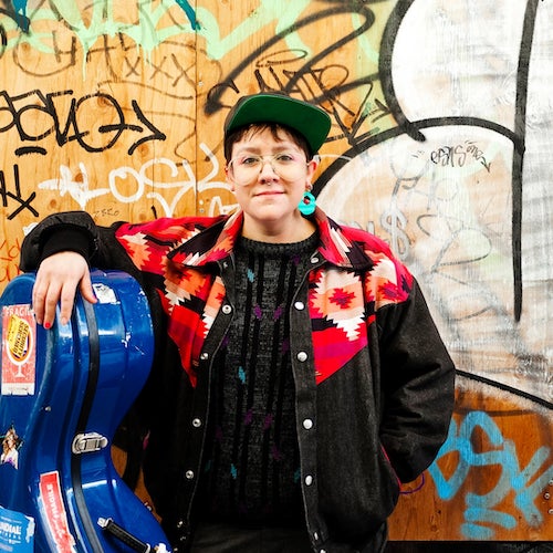 Cris Derkson stands with a cello case.