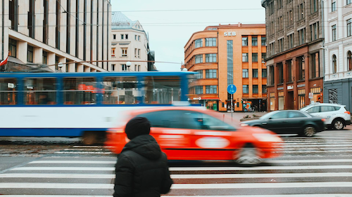 Buses, cars and pedestrians in motion in a busy urban environment.