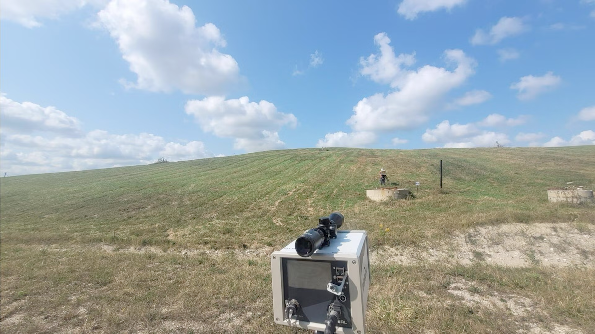 Methane detection equipment on a hillside with blue skies and clouds overhead.