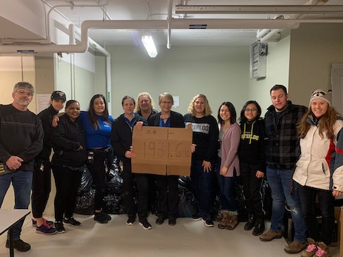Murray Zink stands with a group of volunteers holding a sign that says they diverted more than 1,900 pounds of waste from the landfill.