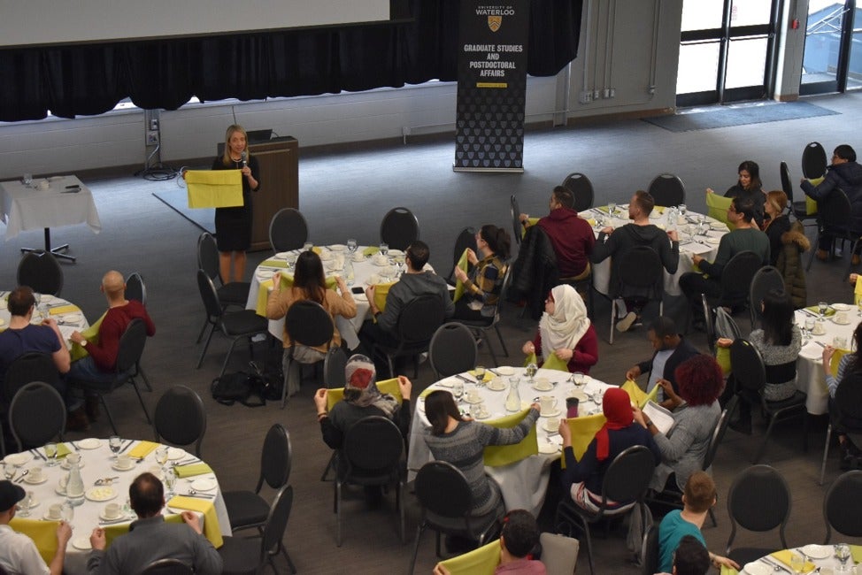 Postdocs and PhD students learning how to fold their napkin, at a Dining Etiquette workshop on April 2.