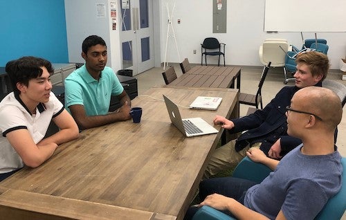 Student entrepreneurs sit around a table.