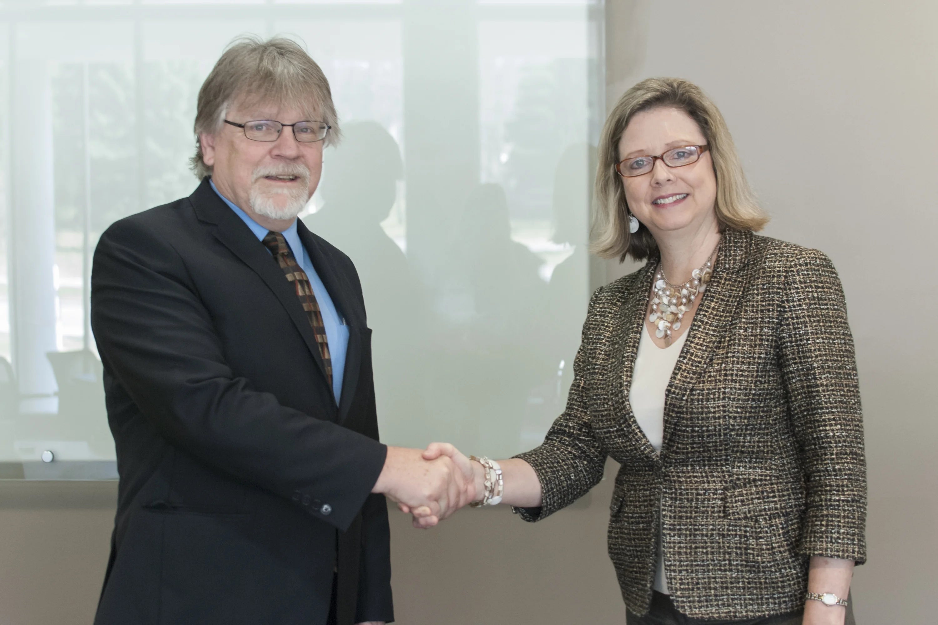 Fred Redekop and Susan Schultz Huxman shake hands.