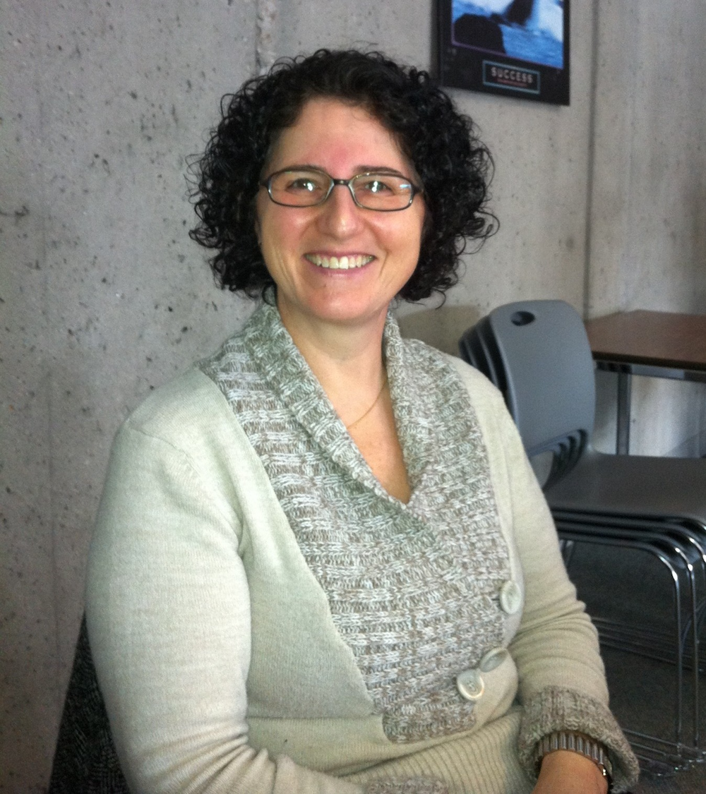 Pam De Leo sits in her office, smiling.