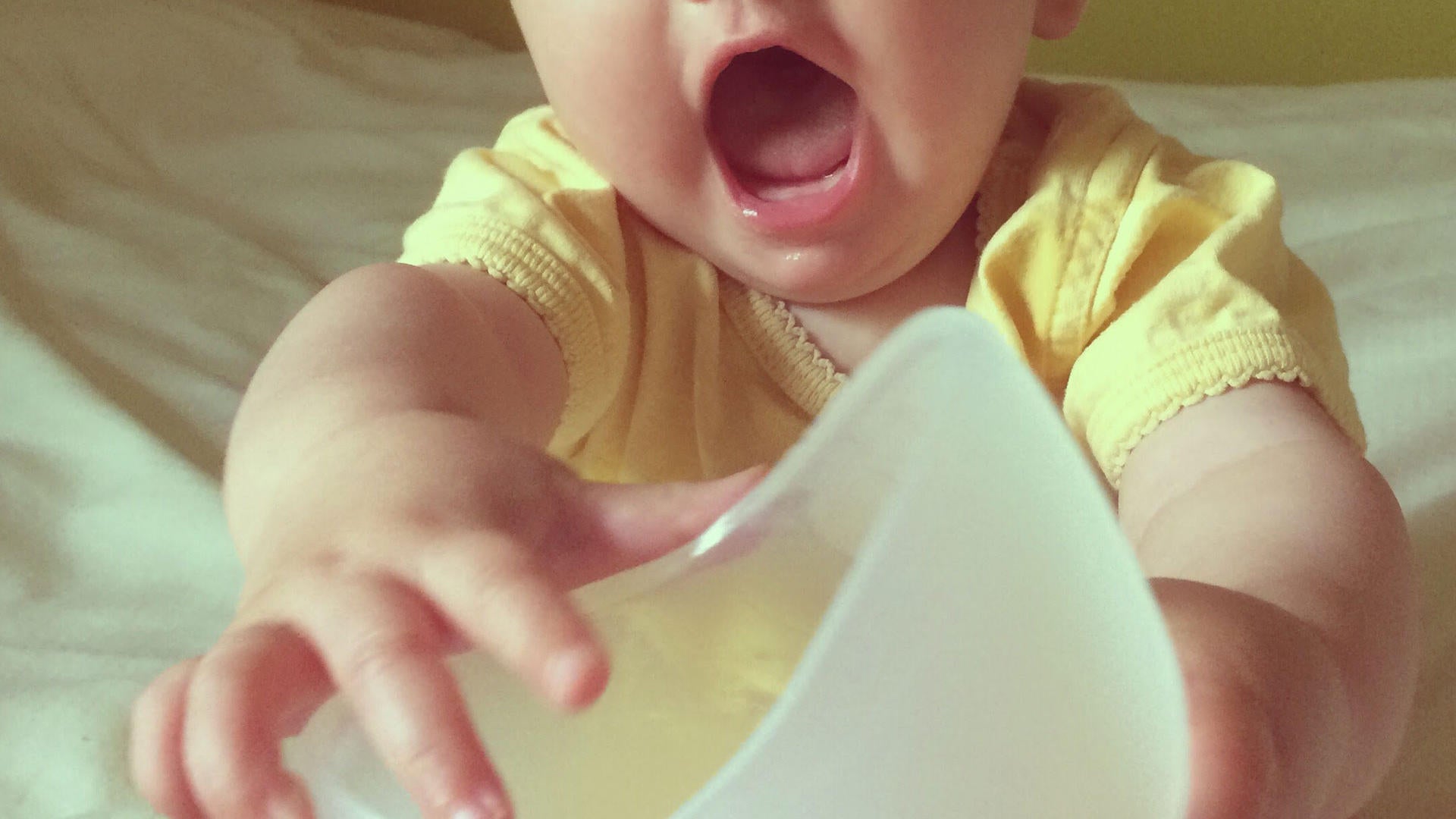 A baby reaches for the Breastbowl pump.