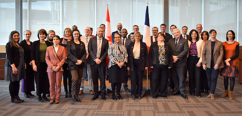 Dignitaries from France and the University of Waterloo pose for a group photo with the national flags of Canada and France.