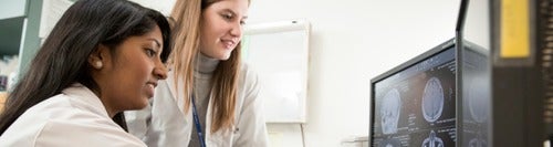 Two women look at a computer screen.