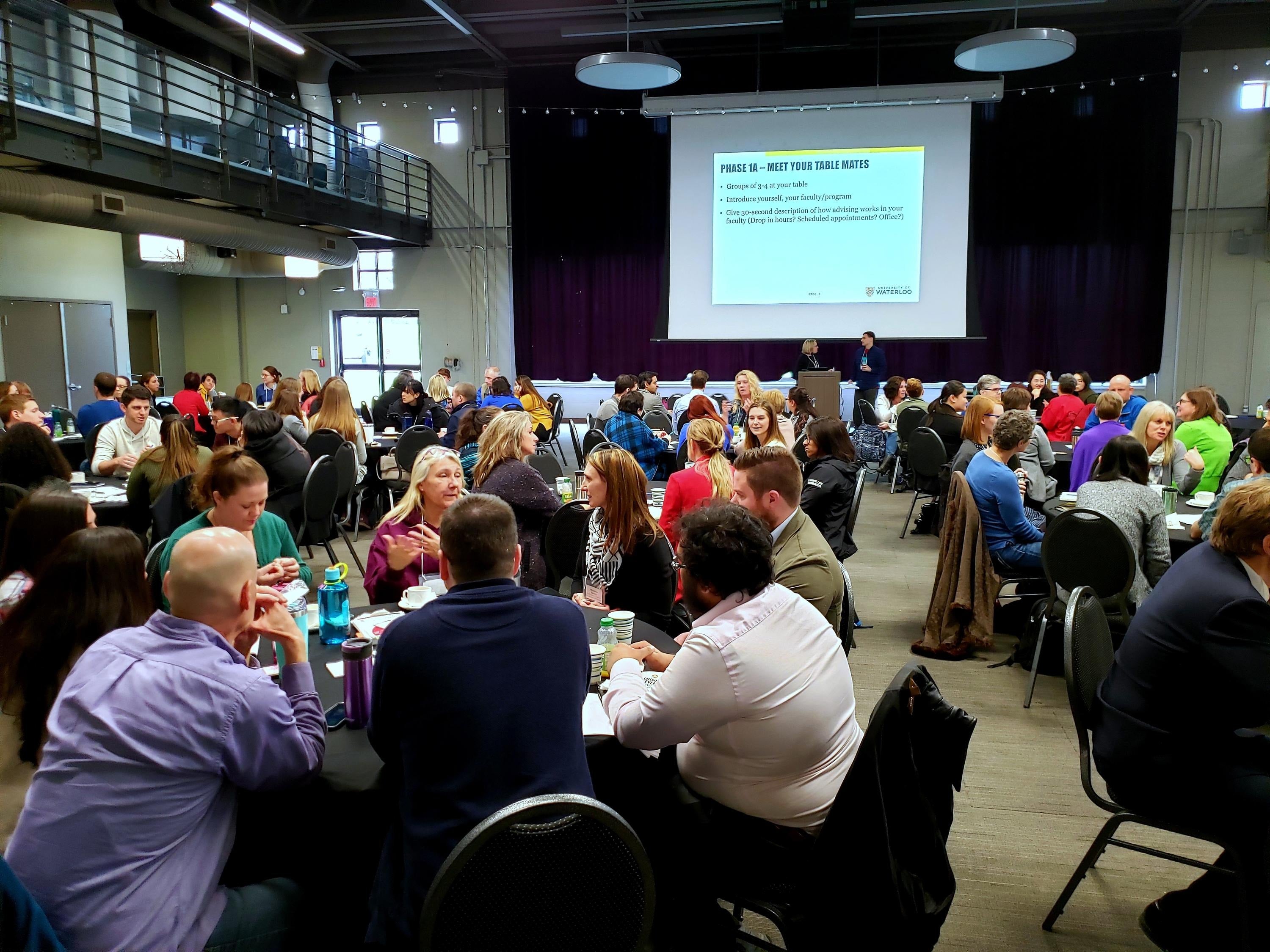 Participants in the advisor conference sit at tables.