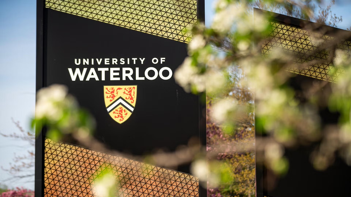 The University of Waterloo sign with tree blossoms in the foreground.