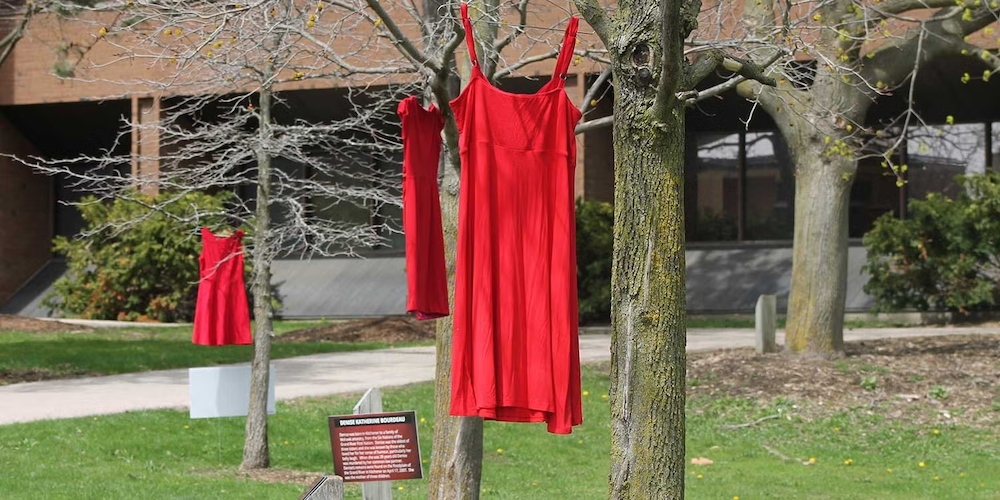 Red dresses hang from trees next to the BMH building.