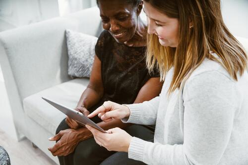 Two women use a tablet device.