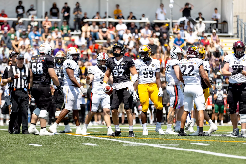 Football players wearing "east" and "west" jerseys on the field.